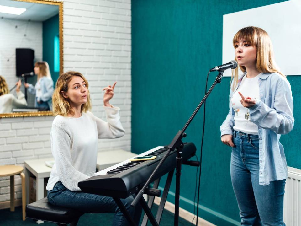 Singing student with her teacher in front of an electronic piano