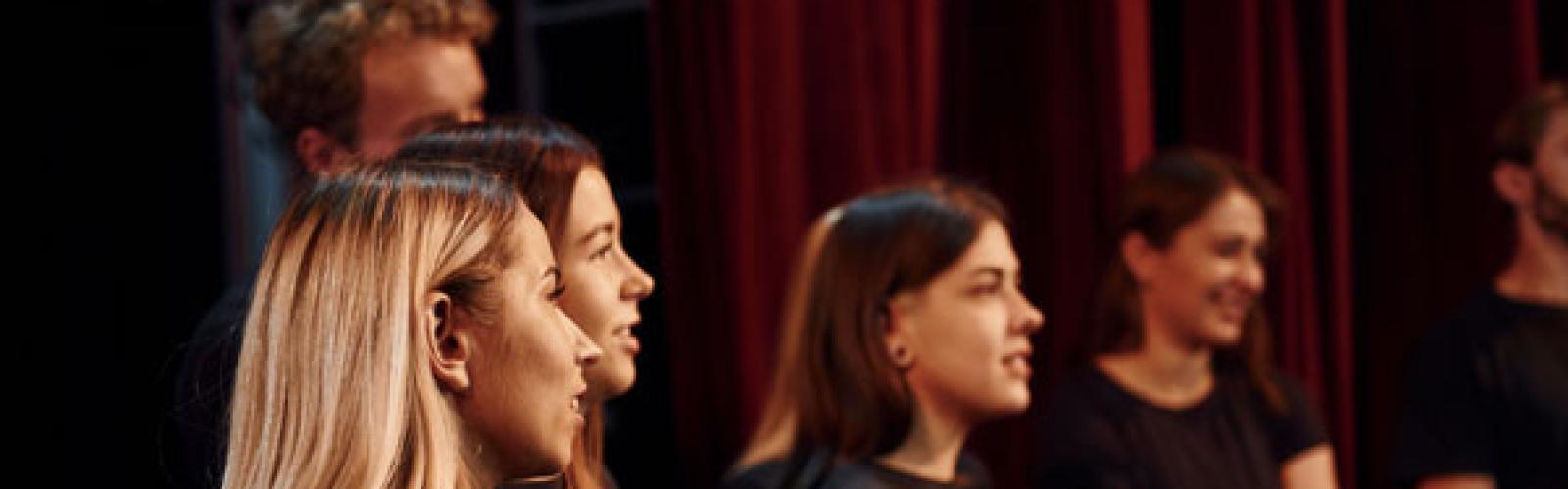 Side view. Group of actors in dark colored clothes on rehearsal in the theater